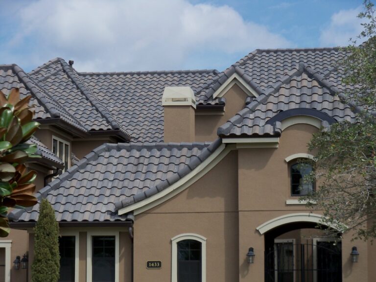 Large European-style country home with gray clay roof tiles and dormer windows.