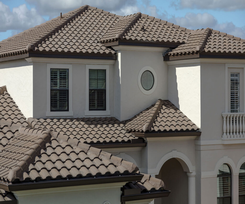 Stone façade home with brown clay roof tiles and arched entryway.