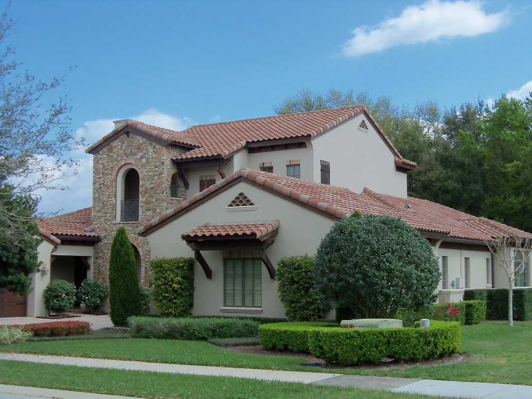 Capistrano Mediterranean-style house with red clay barrel roof tiles and arched stone entrance.