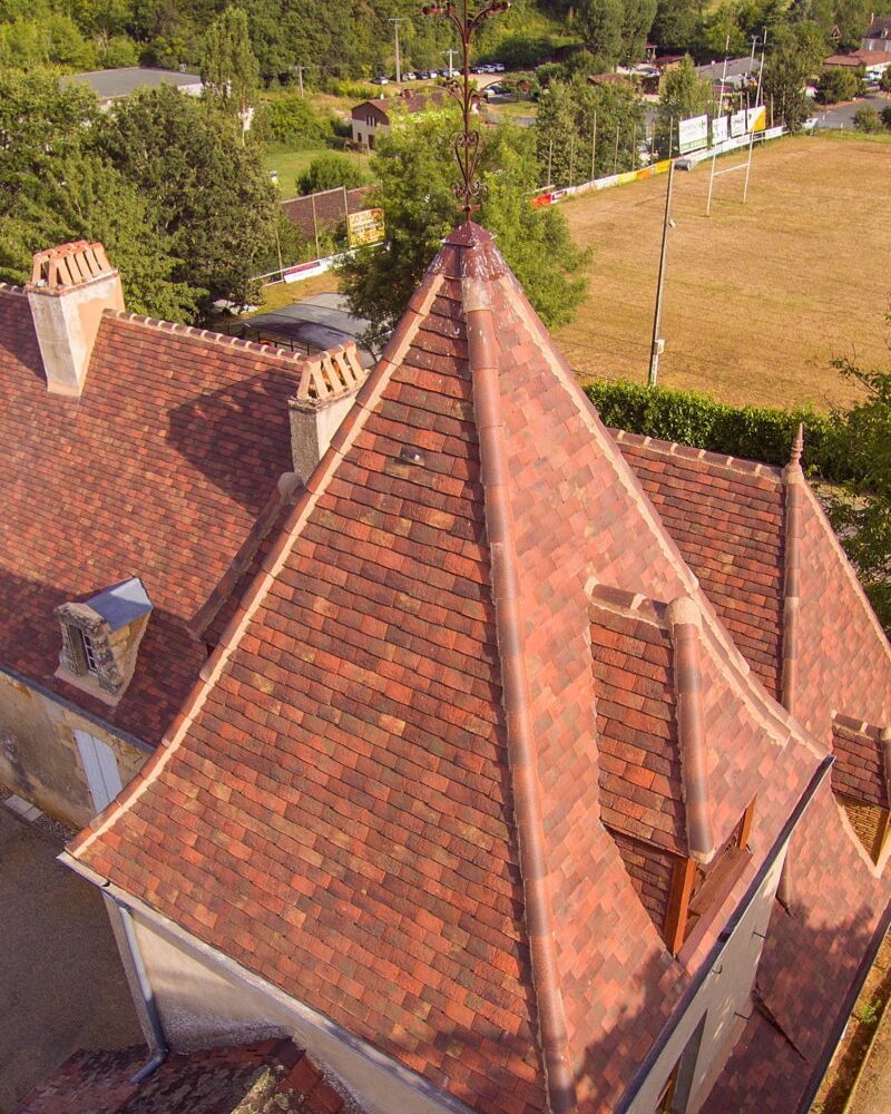 Steep-pitched English and French country roof with aged clay tiles in blended tones.