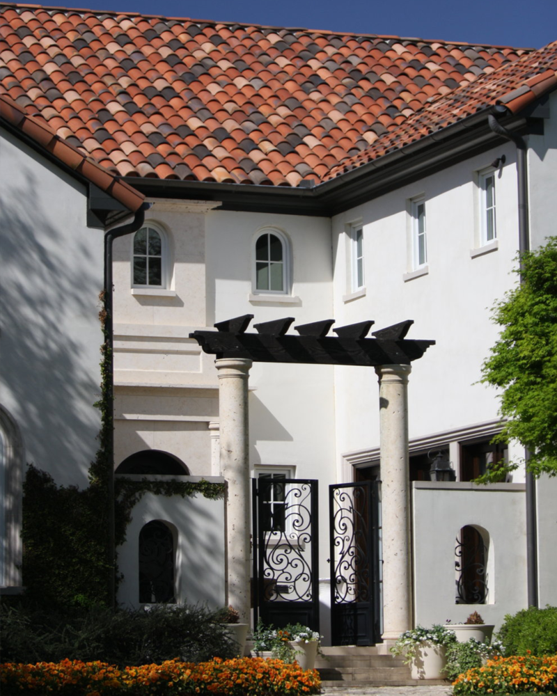 Spanish Mediterranean-style home with red clay barrel roof tiles and white stucco walls.