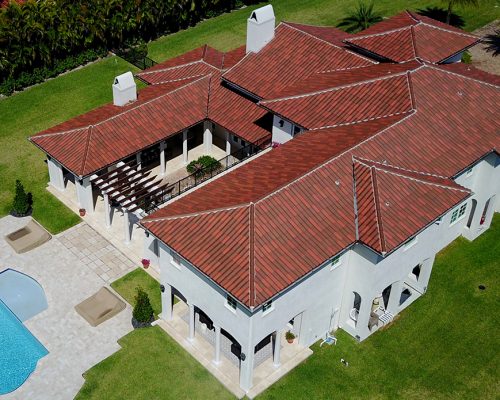 Spanish S roof blend Aerial view of a luxury villa with red terracotta clay roof tiles and white stucco walls.